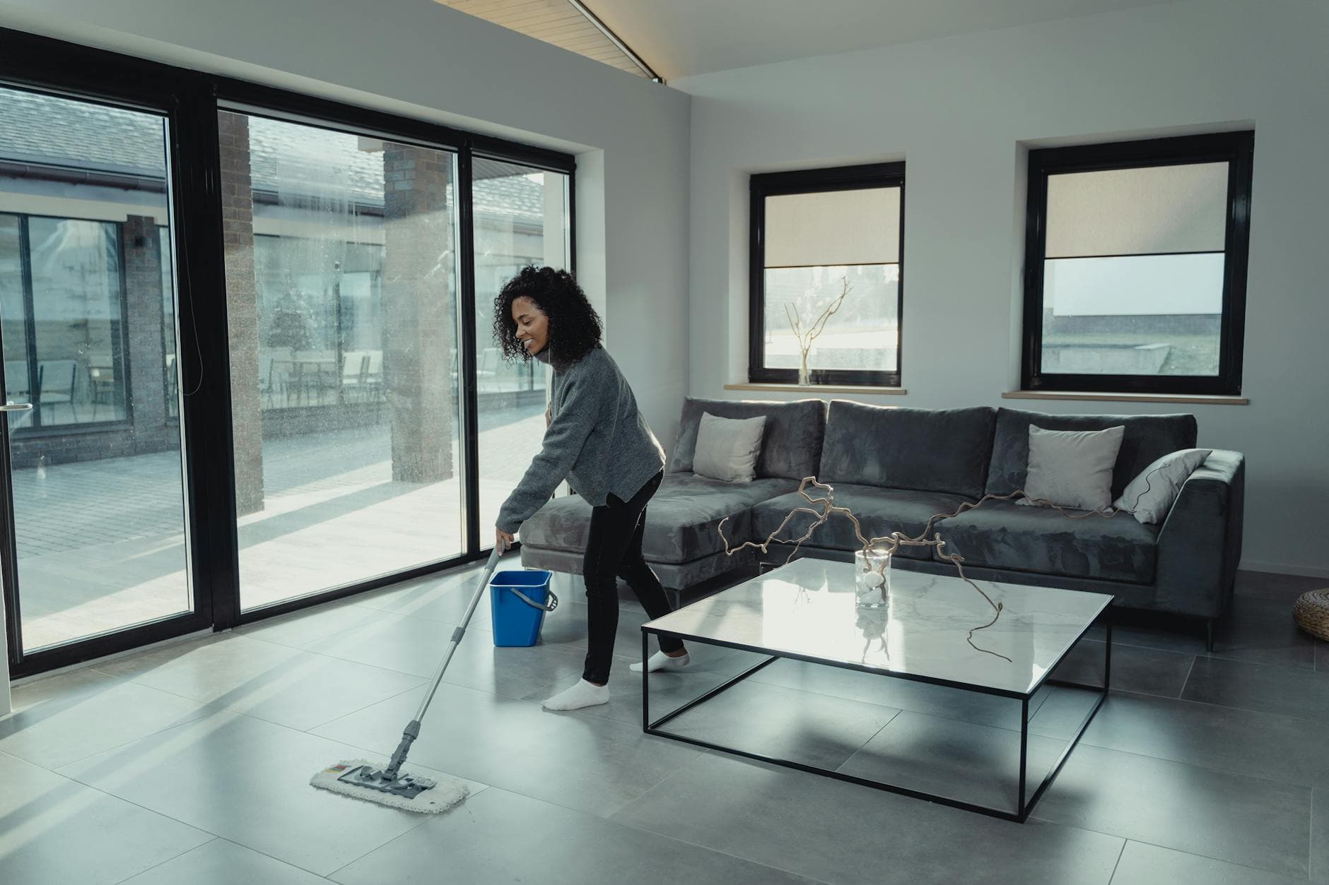 House cleaner mopping a bright, modern NYC apartment with large windows — cleaning services in Edgewater, New Jersey