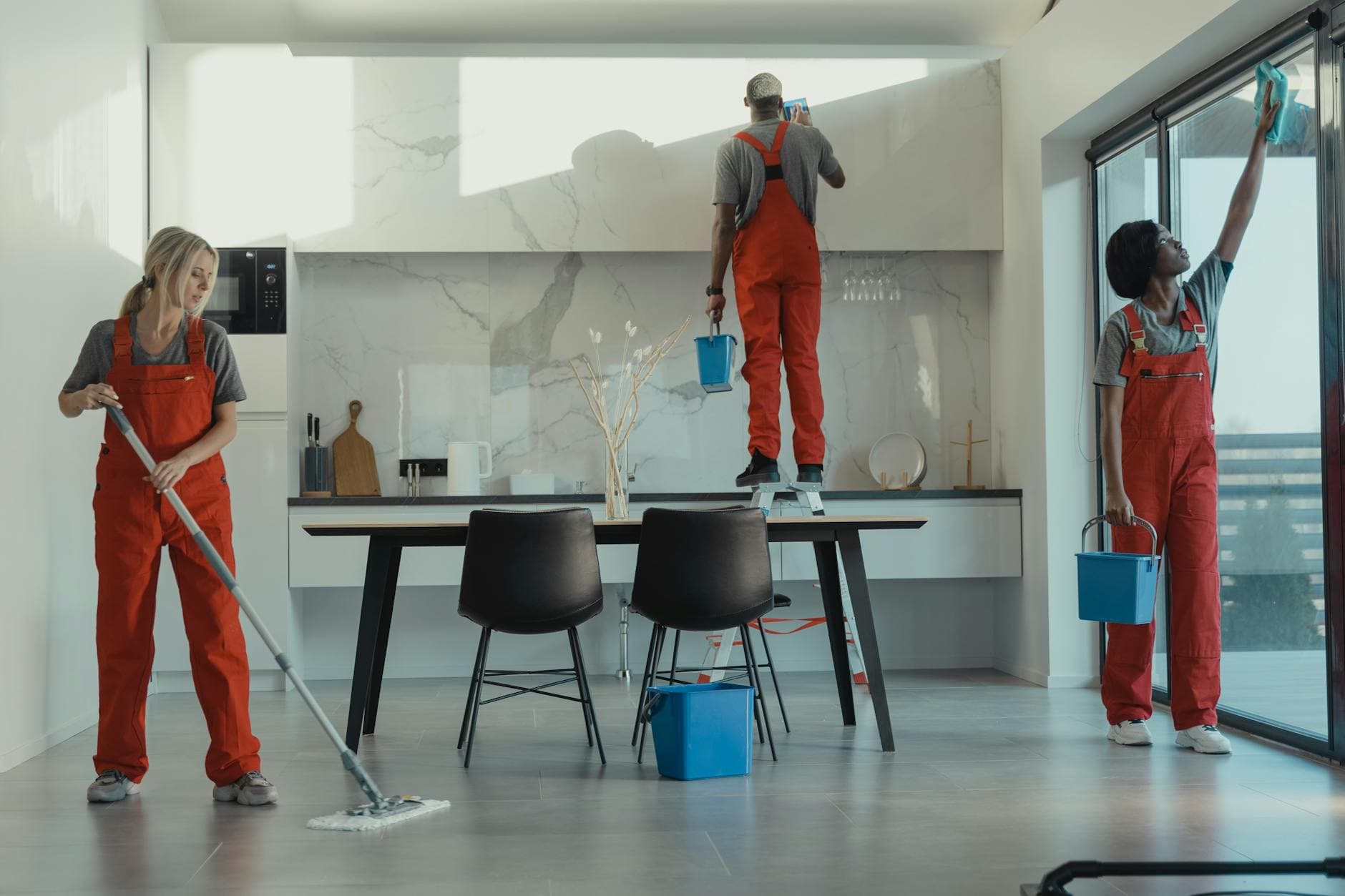 The NYC Maid cleaning crew in red uniforms mopping and wiping glass in a New York dining room — Office Cleaning in Rye, Westchester