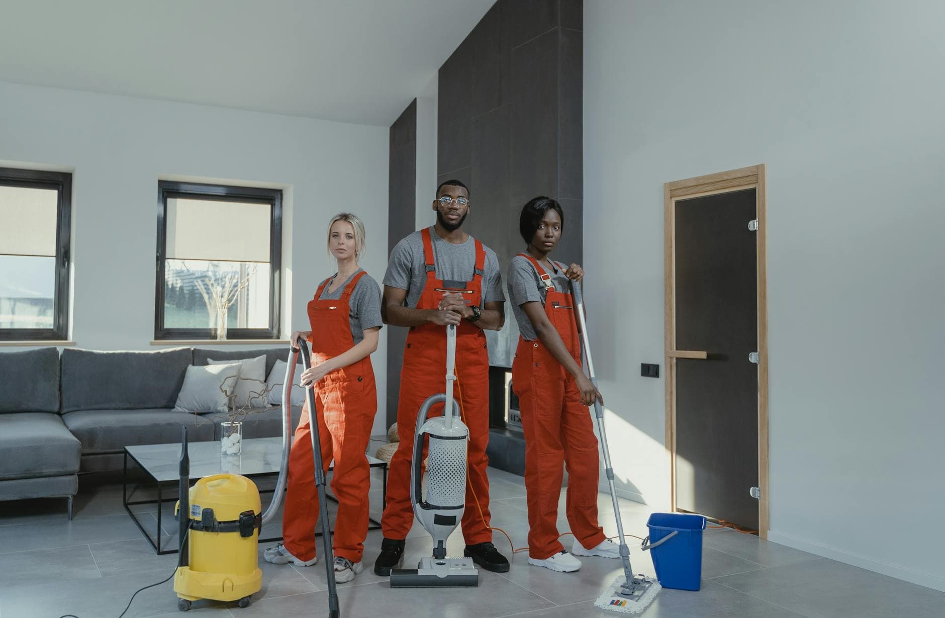 The NYC Maid cleaning team in red uniforms ready to sanitize a modern Manhattan living room — Post-Construction Cleanup in Flushing, Queens