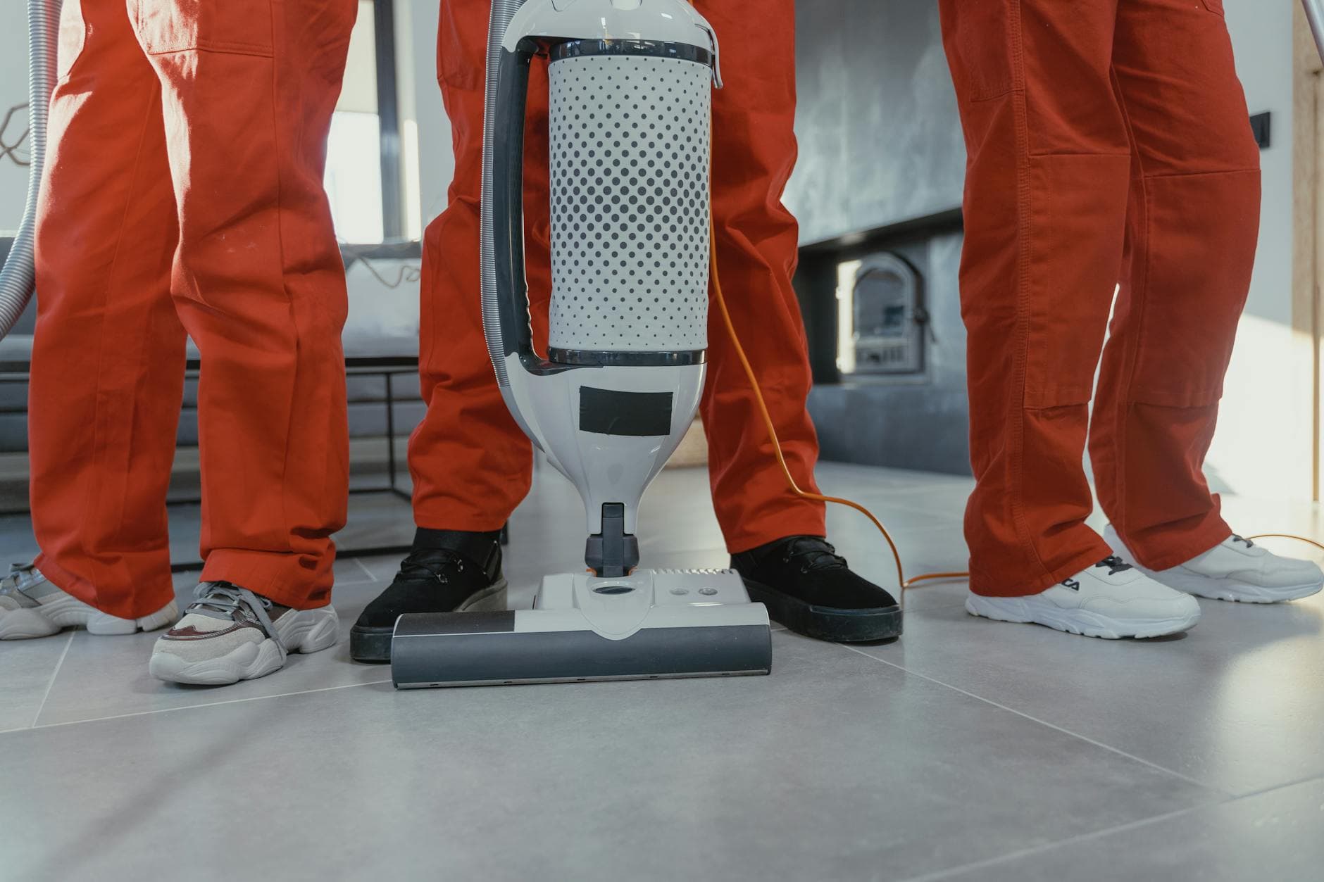 A team of professional NYC Maid cleaners in red uniforms using a vacuum in a New York home — Same-Day Cleaning in NYC