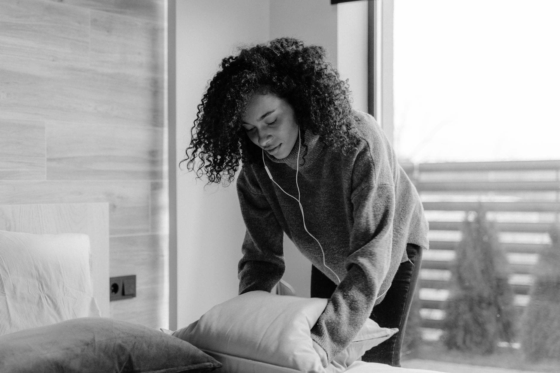 NYC maid service making the bed in a bright, monochrome bedroom — cleaning services in Morris Park, Bronx
