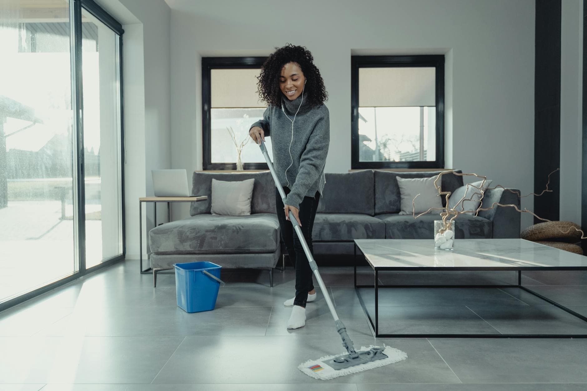 A maid from The NYC Maid mopping a tiled floor in a cozy New York City apartment — cleaning services in Flushing, Queens
