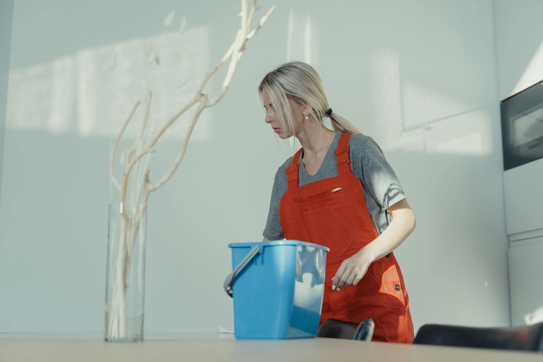 Professional cleaner from The NYC Maid in red uniform cleaning an NYC apartment with a bucket — Post-Construction Cleanup in NYC